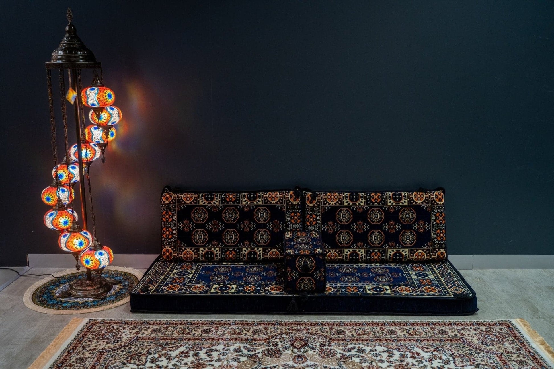 Arabian Majlis Divan Set featuring navy diamond cushions and ornate floor lamp in a stylish living space.