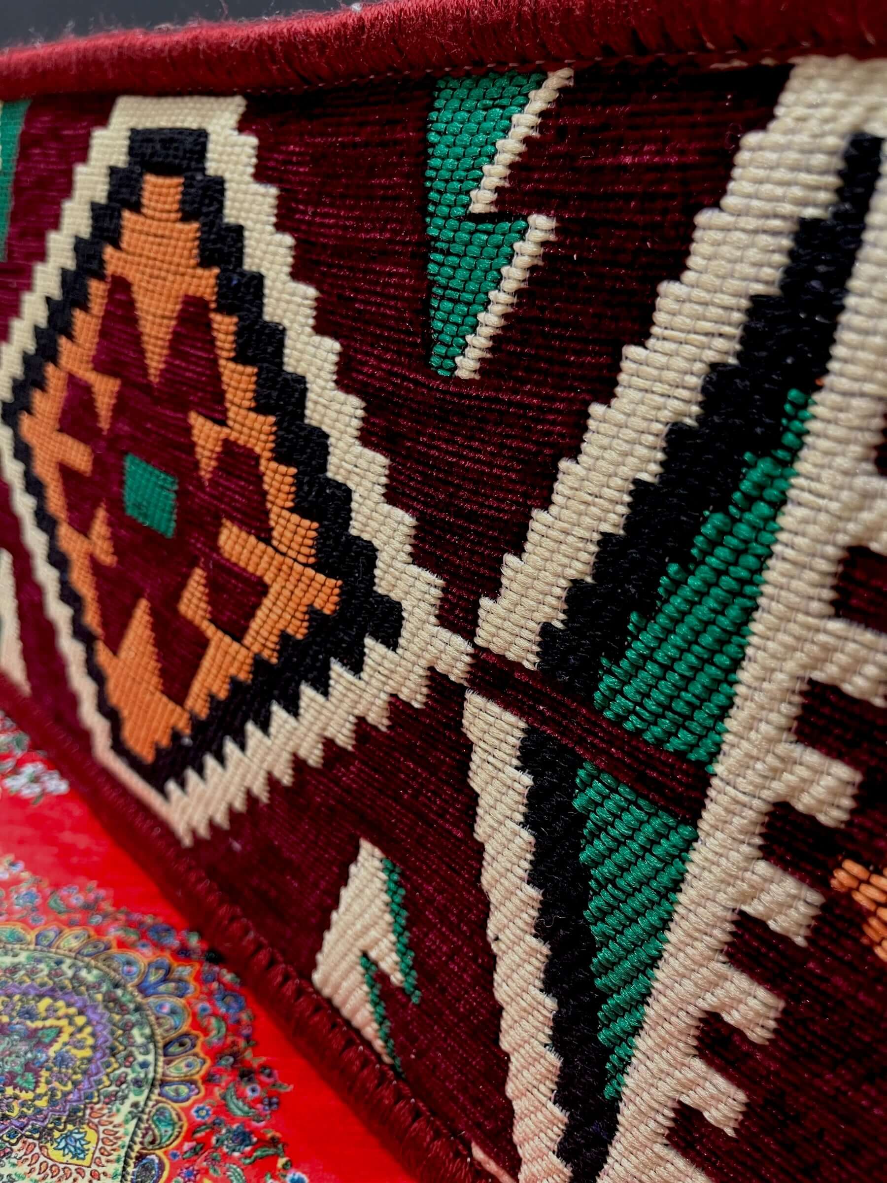 Traditional Turkish Armrest detailed embroidery showcasing vibrant patterns and colors on a maroon background.