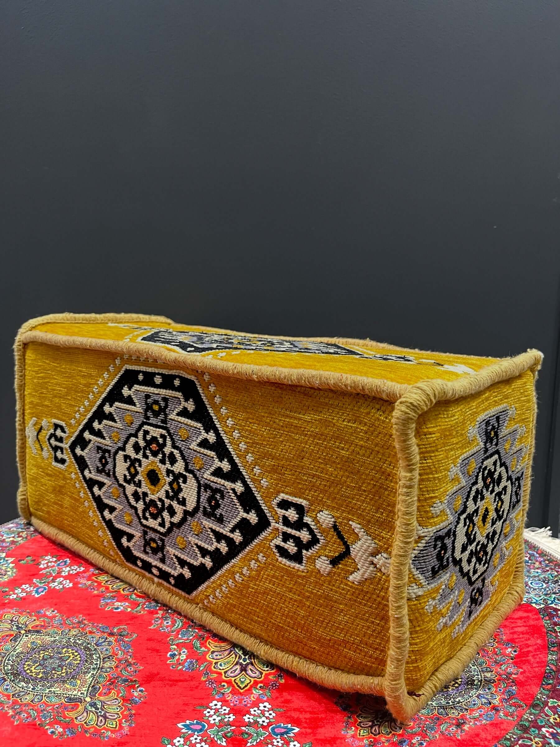Traditional Turkish Armrest Cushion in vibrant yellow with intricate patterns on a colorful background.