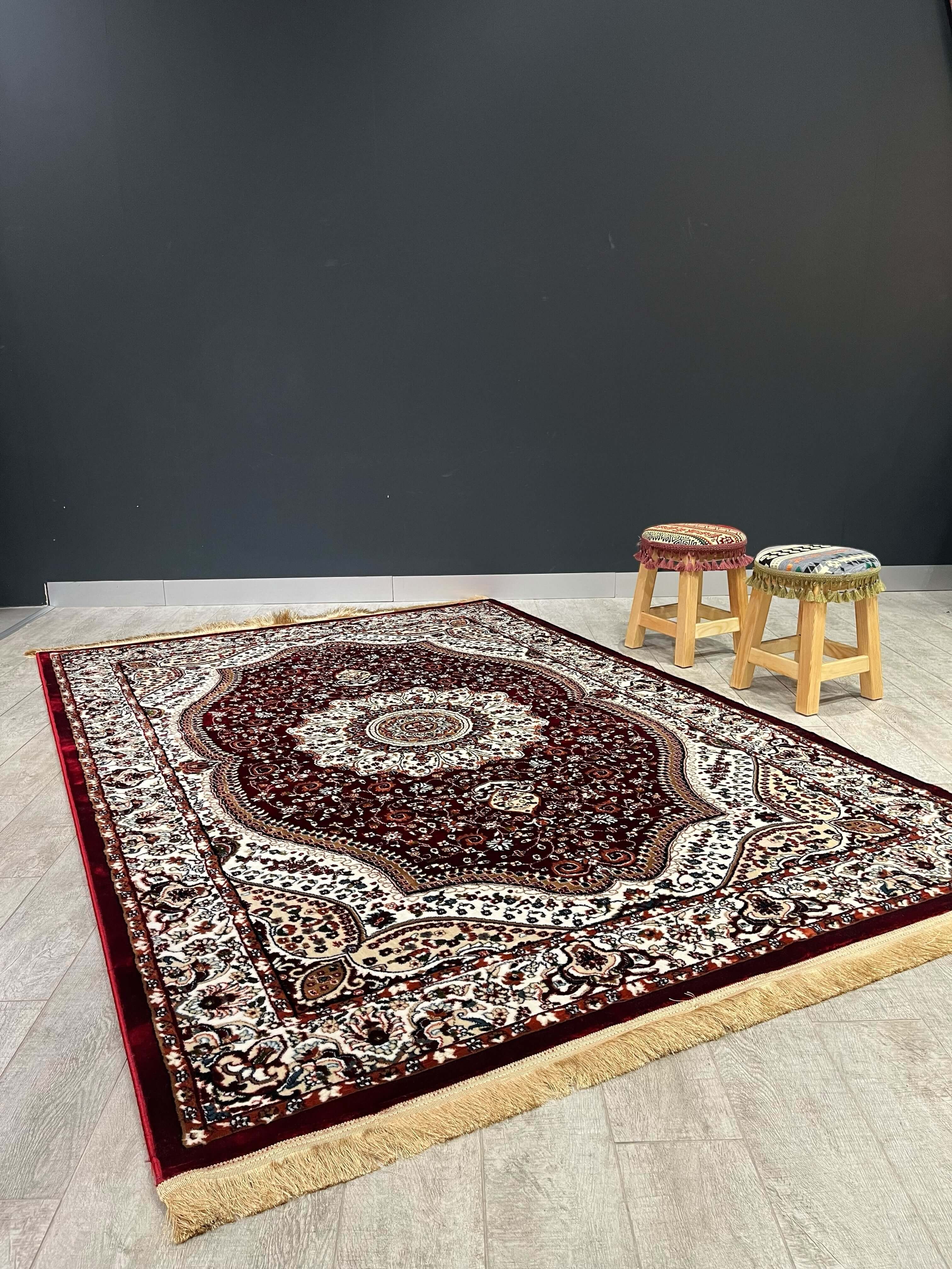 Asaryun Turkish Rug – H4158A Dark Red displayed on a floor with wooden stools, showcasing its intricate traditional design.