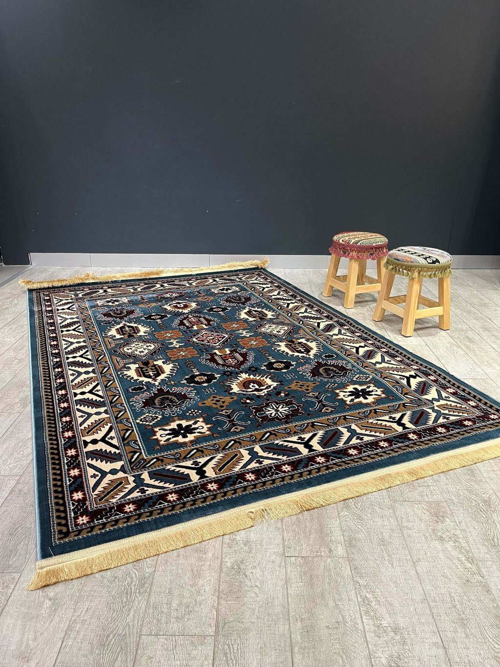Asaryun Turkish Rug – H4731B Blue displayed on wooden floor with stools in the background.