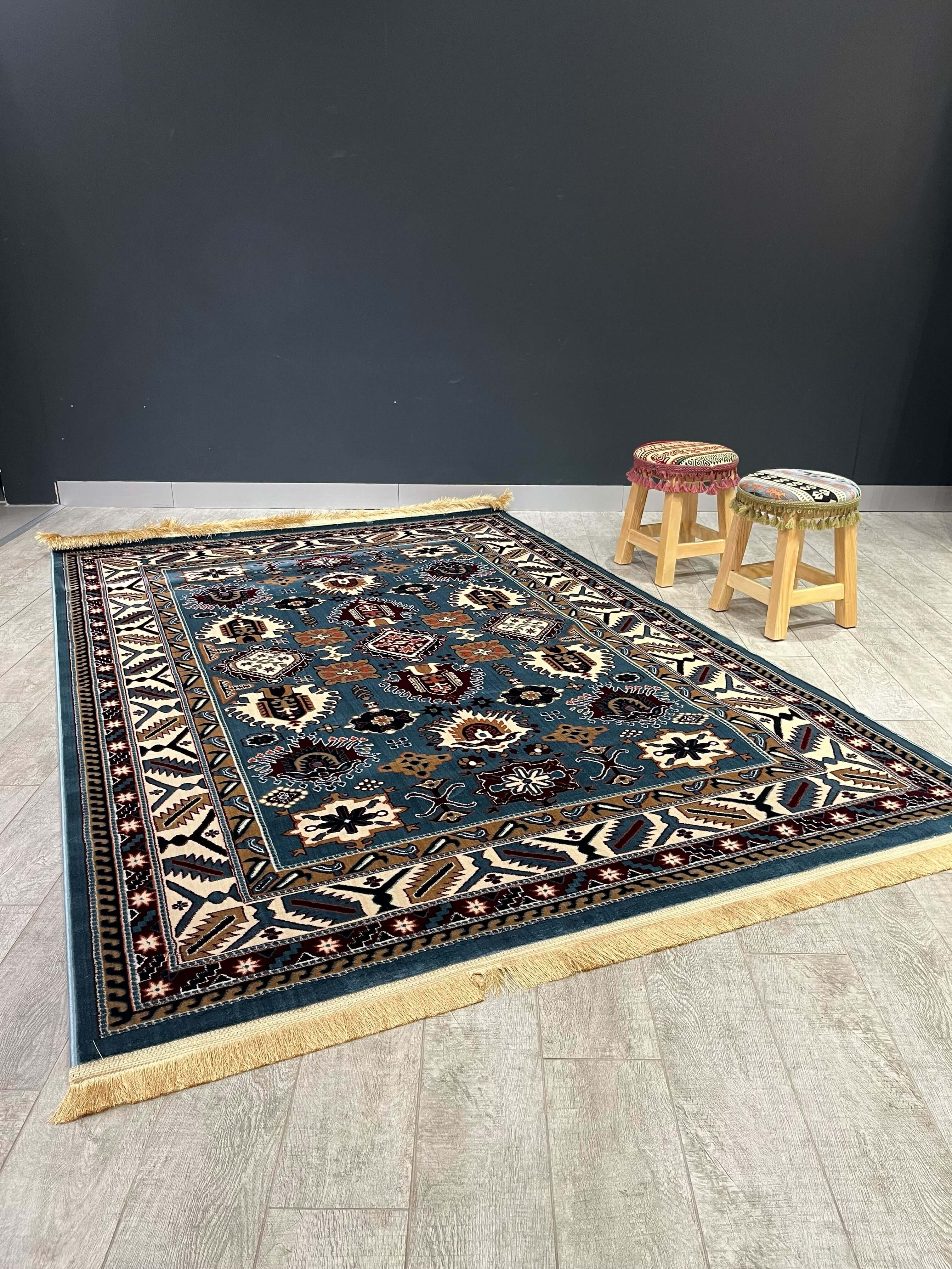 Asaryun Turkish Rug – H4731B Blue displayed on wooden floor with stools in the background.