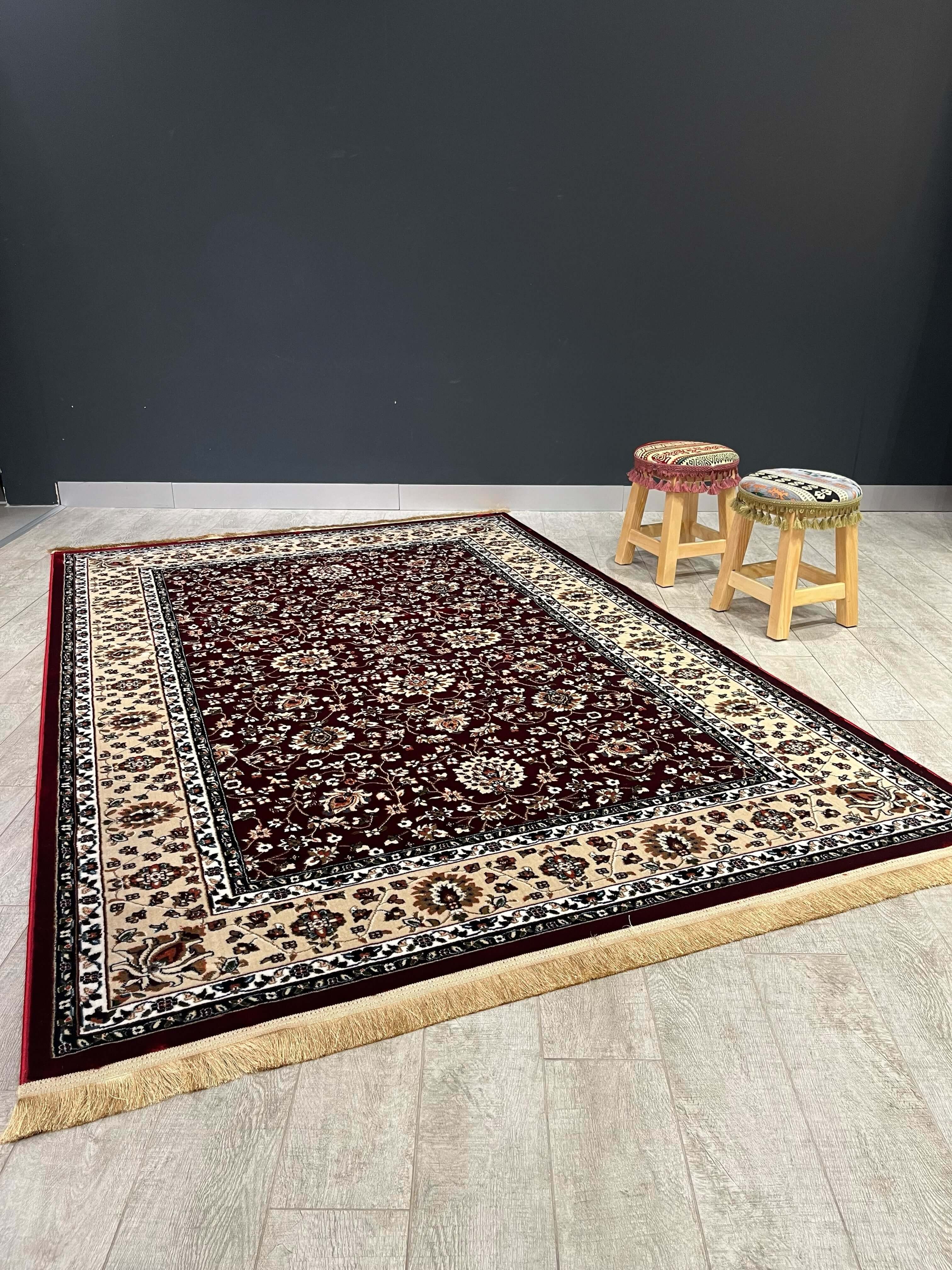 Asaryun Turkish Rug H5500A Dark Red featuring intricate patterns on a wood floor with two wooden stools.