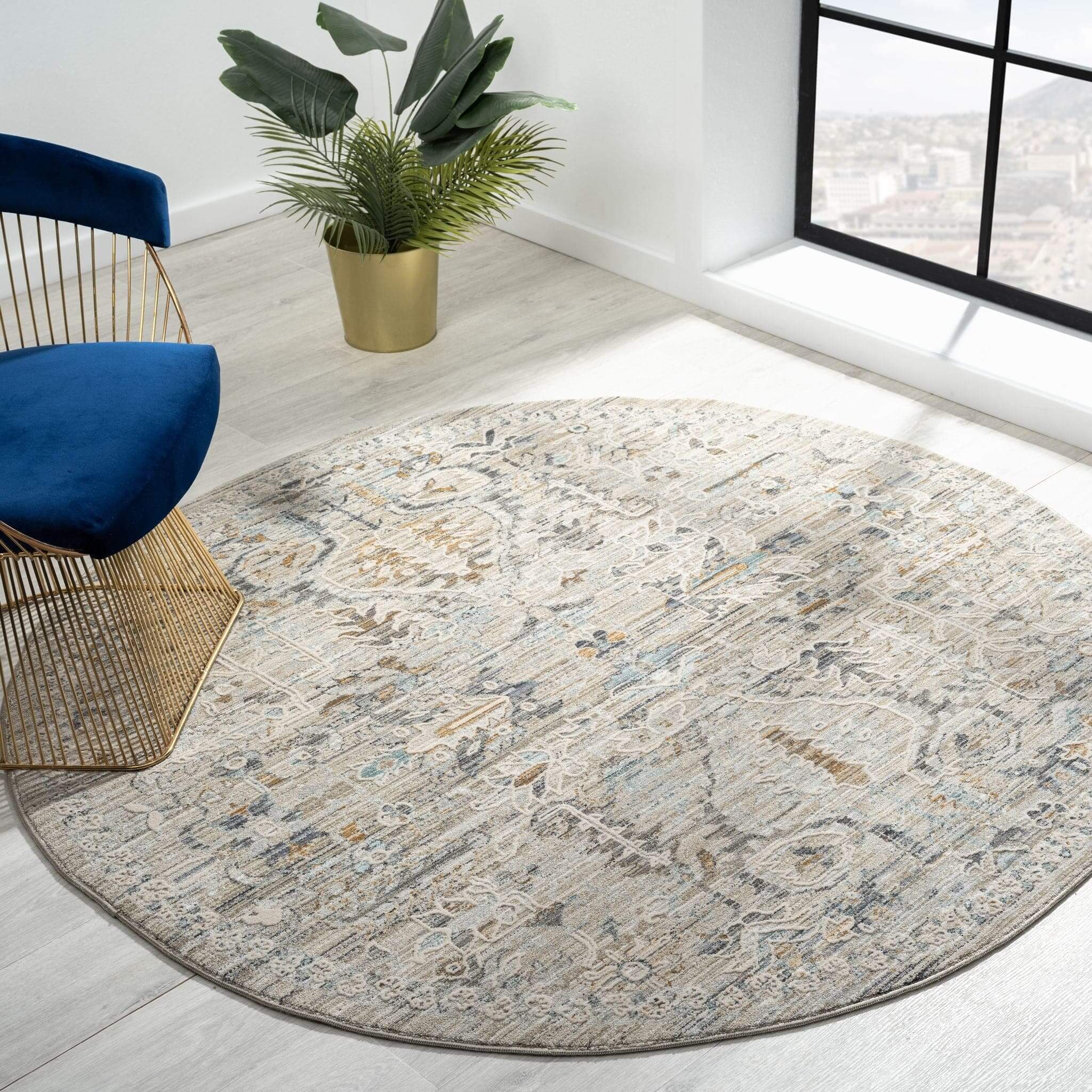 Aubrey 6755 Taupe Round Turkish Rug displayed in a modern room with a blue chair and potted plant.