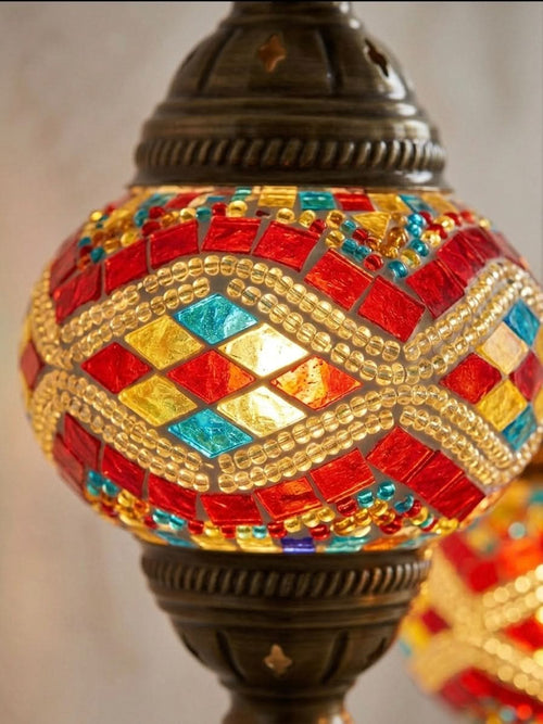 Close-up of a vibrant Turkish mosaic table lamp with red, blue, and yellow diamond patterns.