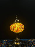 Mosaic Table Lamp with vibrant yellow and orange glass design on a decorative base, illuminating a cozy space.