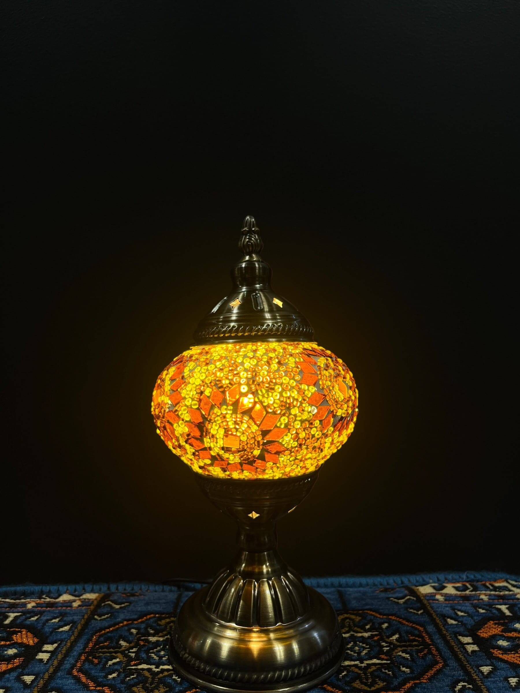 Mosaic Table Lamp with vibrant yellow and orange glass design on a decorative base, illuminating a cozy space.