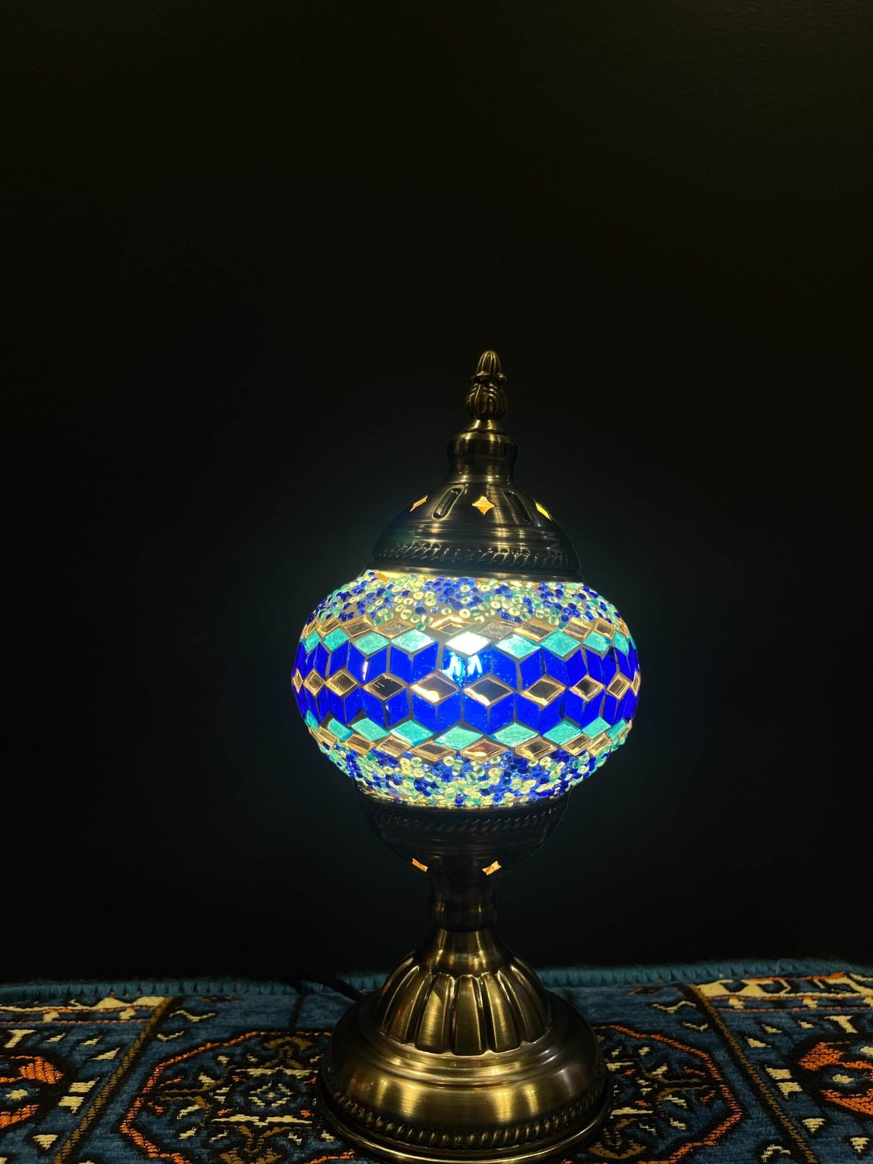 Mosaic Table Lamp featuring a vibrant blue diamond design, casting a warm glow in a stylish setting.