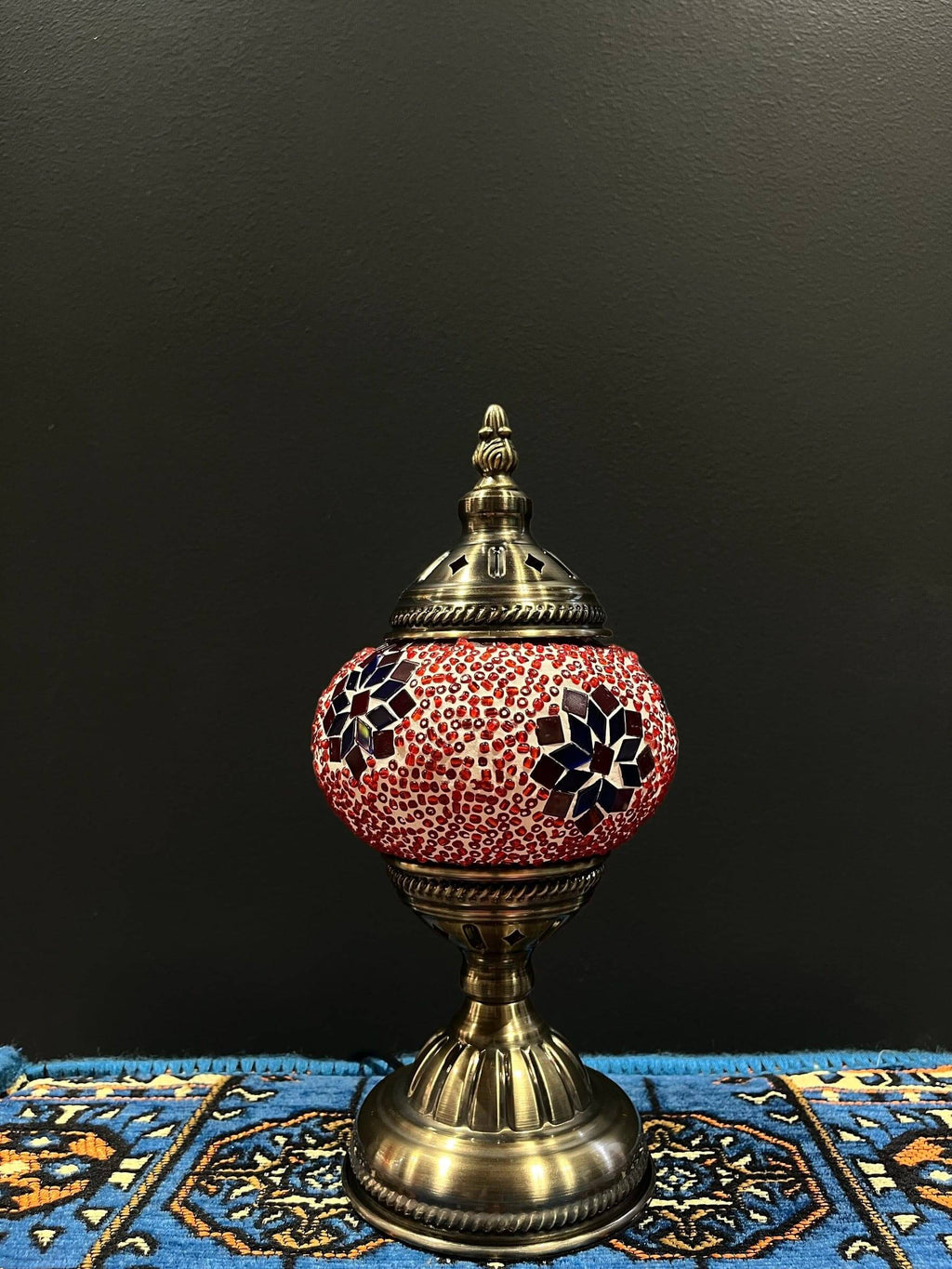 Mosaic Table Lamp with red and blue flower design on glass shade against a dark background.