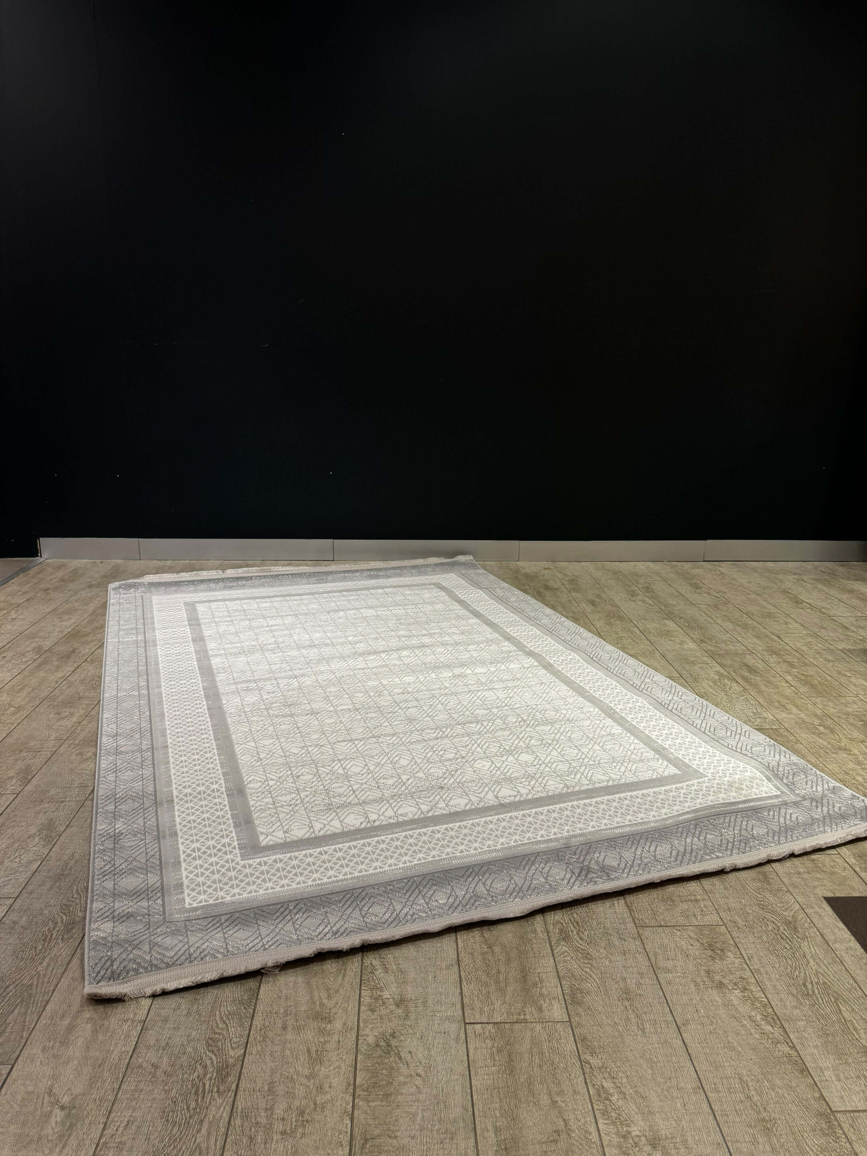 Geometric Border Premium Turkish Rug displayed on wooden floor, featuring a soft neutral base and geometric border.