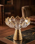 Glass Crystal Fruit Bowl with Gold Stand elegantly displayed on a marble table with books in the background.