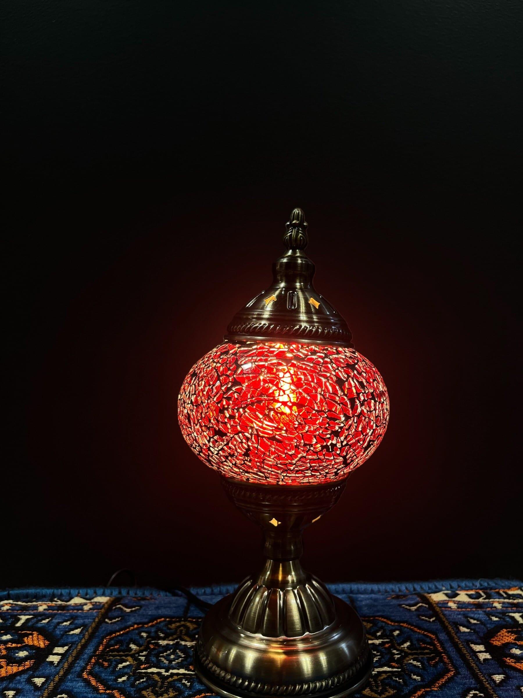 Mosaic Table Lamp with red crackle Turkish glass, illuminating a warm glow on an ornate surface.