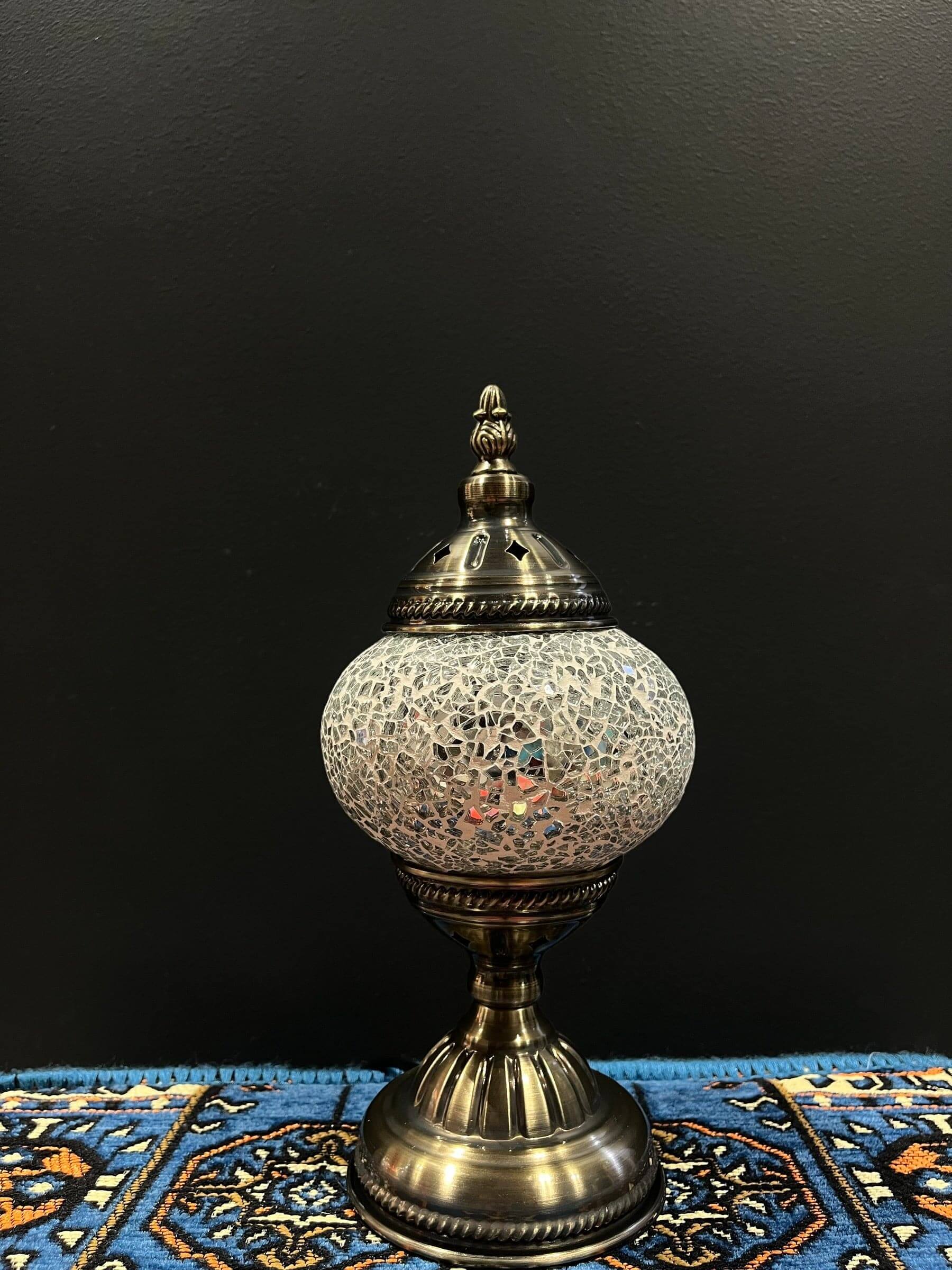 Mosaic Table Lamp with white crackle glass shade and decorative base on colorful rug.