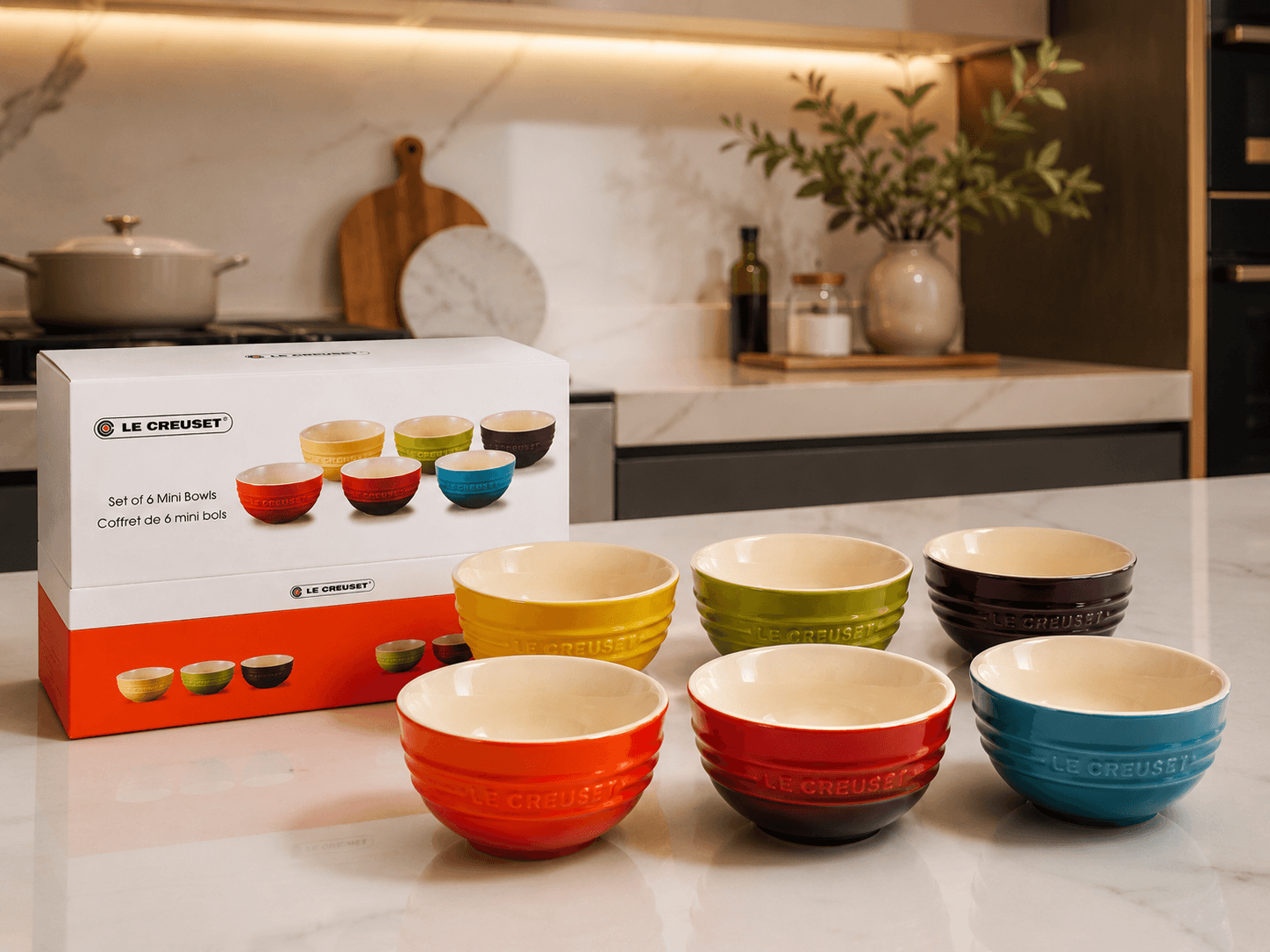 Le Creuset mini stoneware bowls set displayed with vibrant colors and packaging in a modern kitchen.