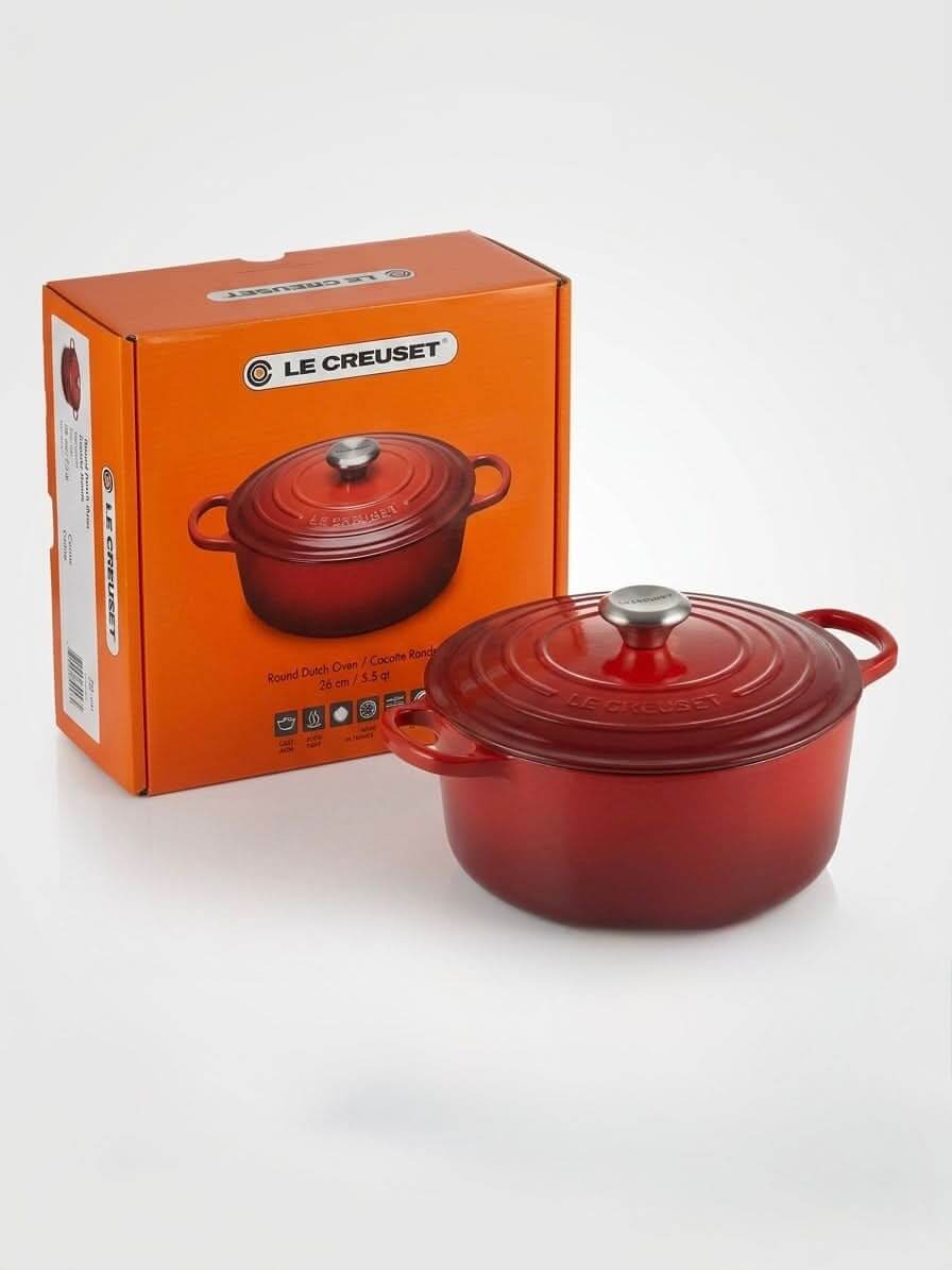 Le Creuset cast iron Dutch oven 26cm with packaging in Cerise Red color, showcasing its design and quality.