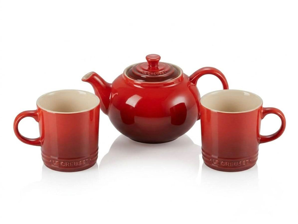 Le Creuset teapot with mugs set in Cerise Red, showcasing elegant design perfect for tea time.