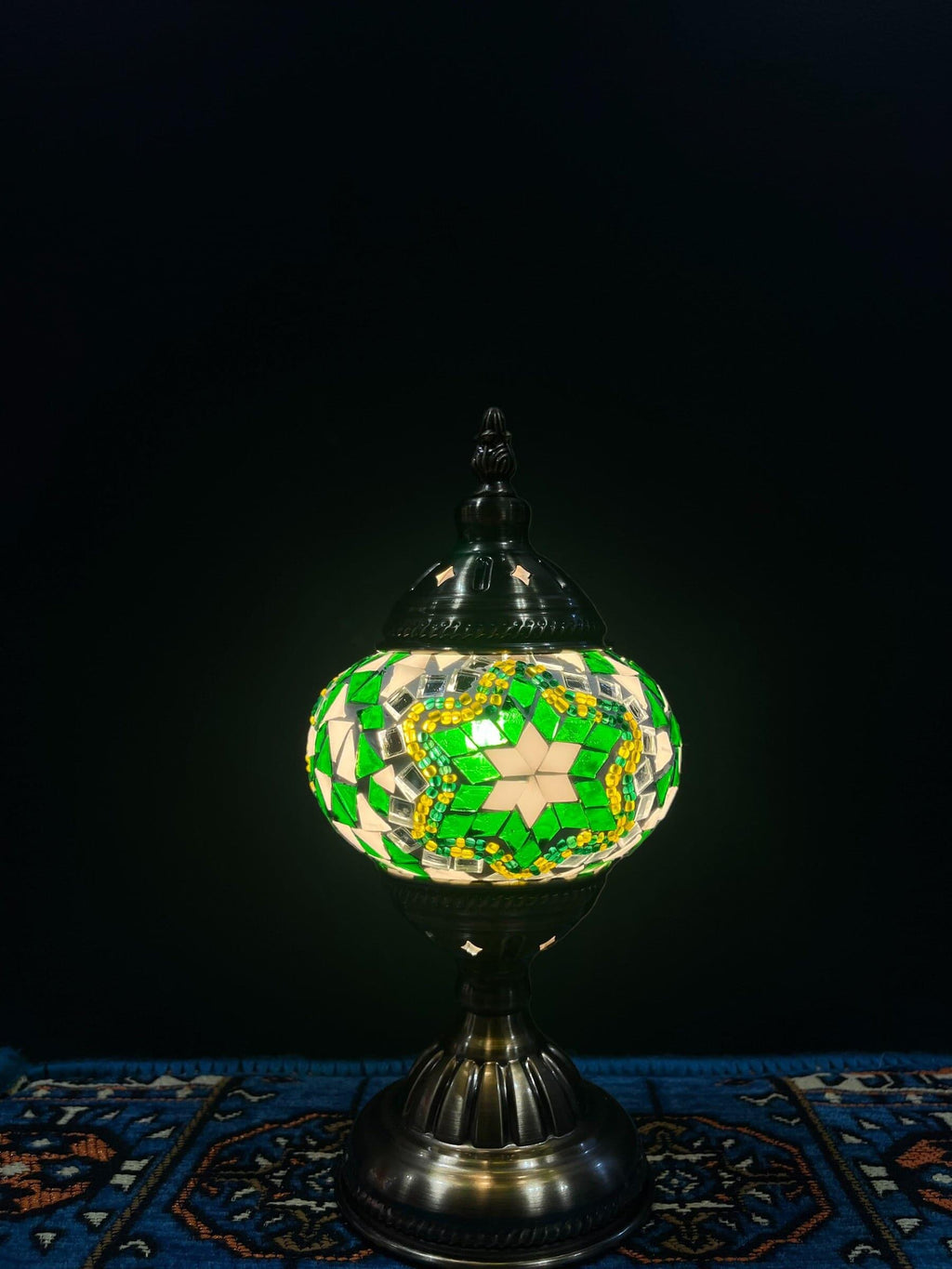 Mosaic Table Lamp with green and white glass mosaic design, illuminating warm light against a dark backdrop.