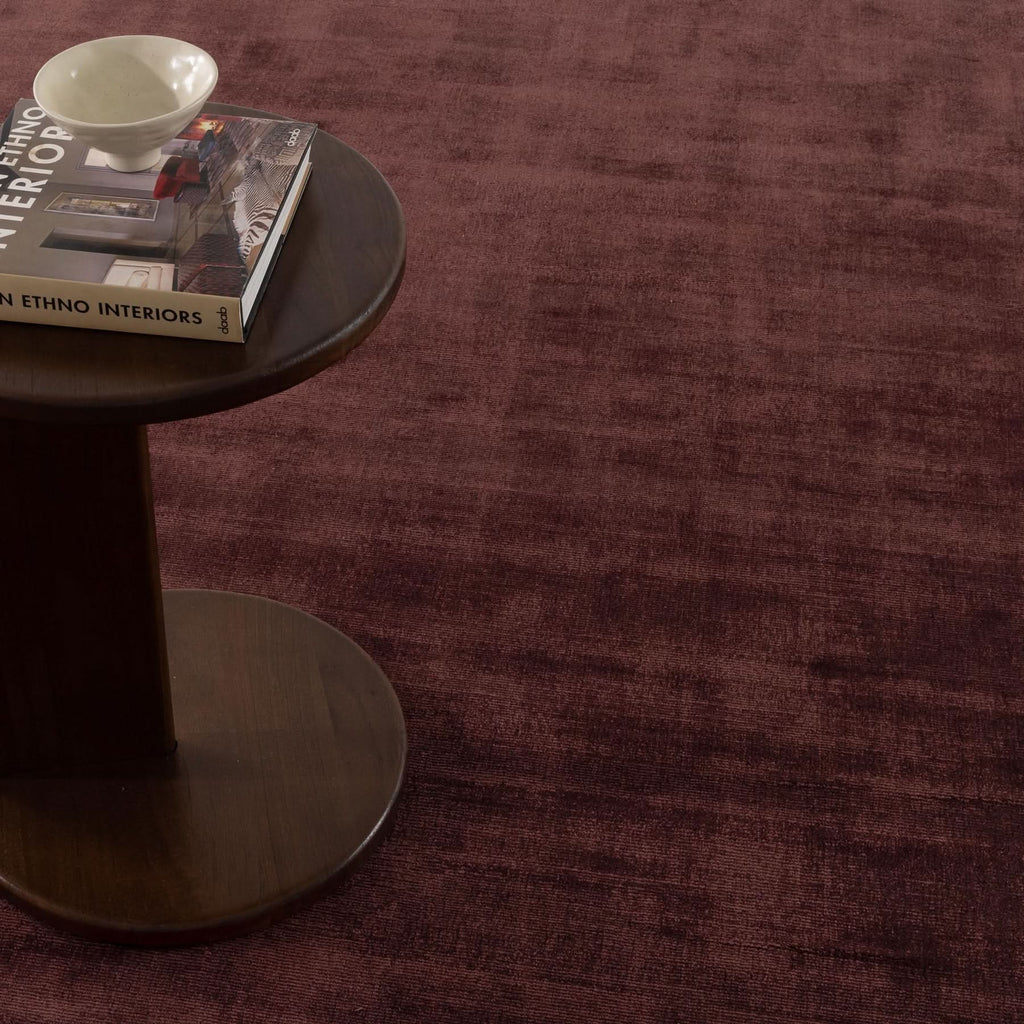 Silken Luxe Chocolate Cherry Rug displayed with a side table and decor, highlighting its luxurious texture and color.