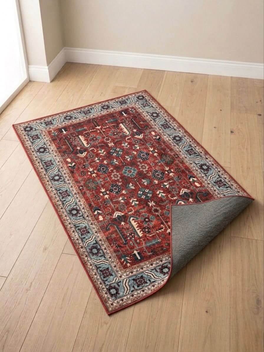 Traditional Red Prayer Mat with blue border, featuring intricate geometric and floral patterns on wooden floor.