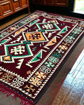 Turkish Kilim Rug – Maroon Serenity with geometric pattern on a wooden floor.