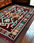 Turkish Kilim Rug – Maroon Serenity with geometric pattern on a wooden floor.