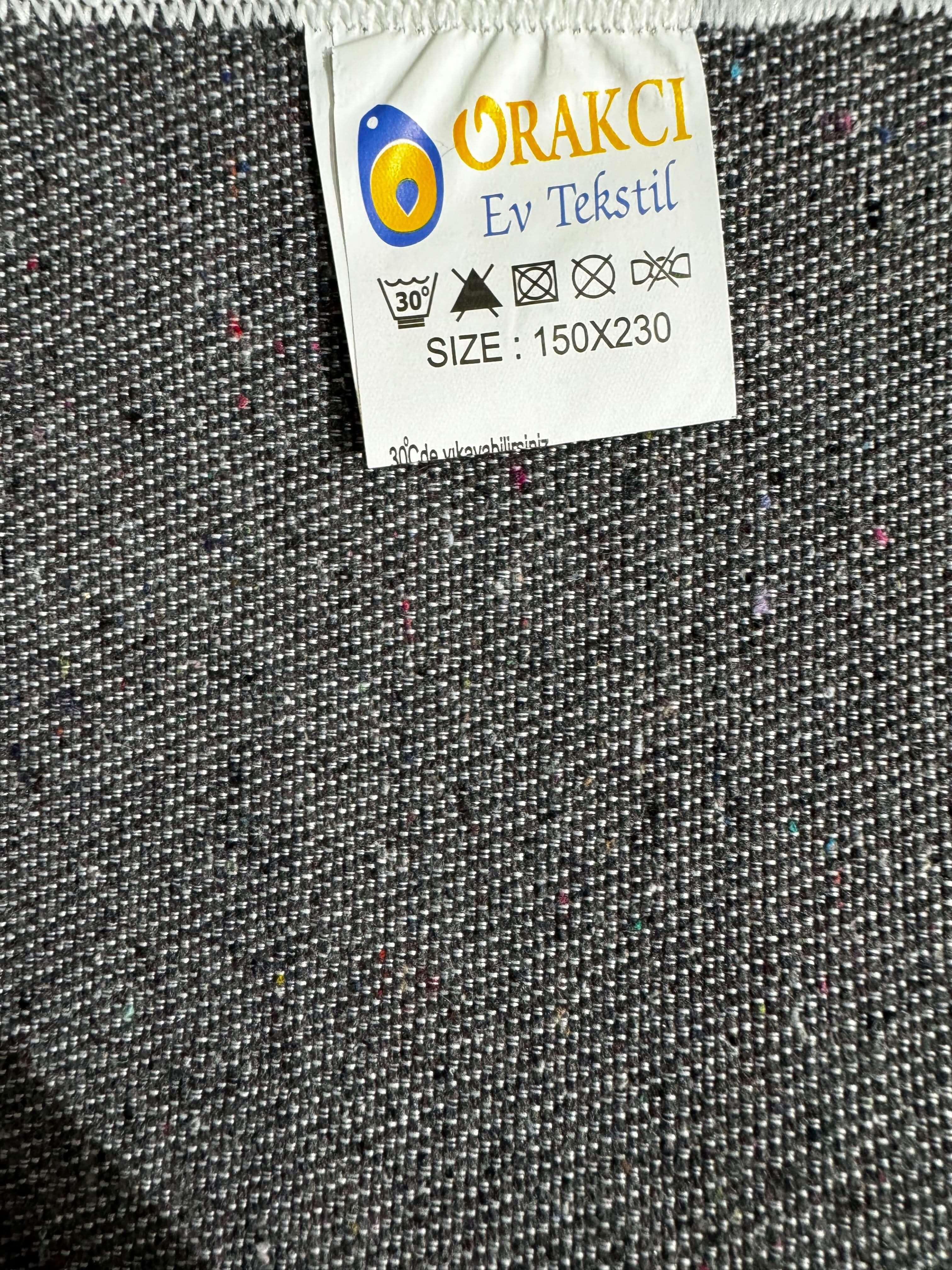 Turkish Rug label with size 150X230 on textured grey fabric background.