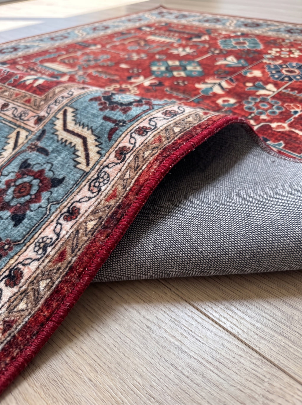 Folded corner of the Anatolian Heritage Turkish rug showing its grey woven backing and red bound edge