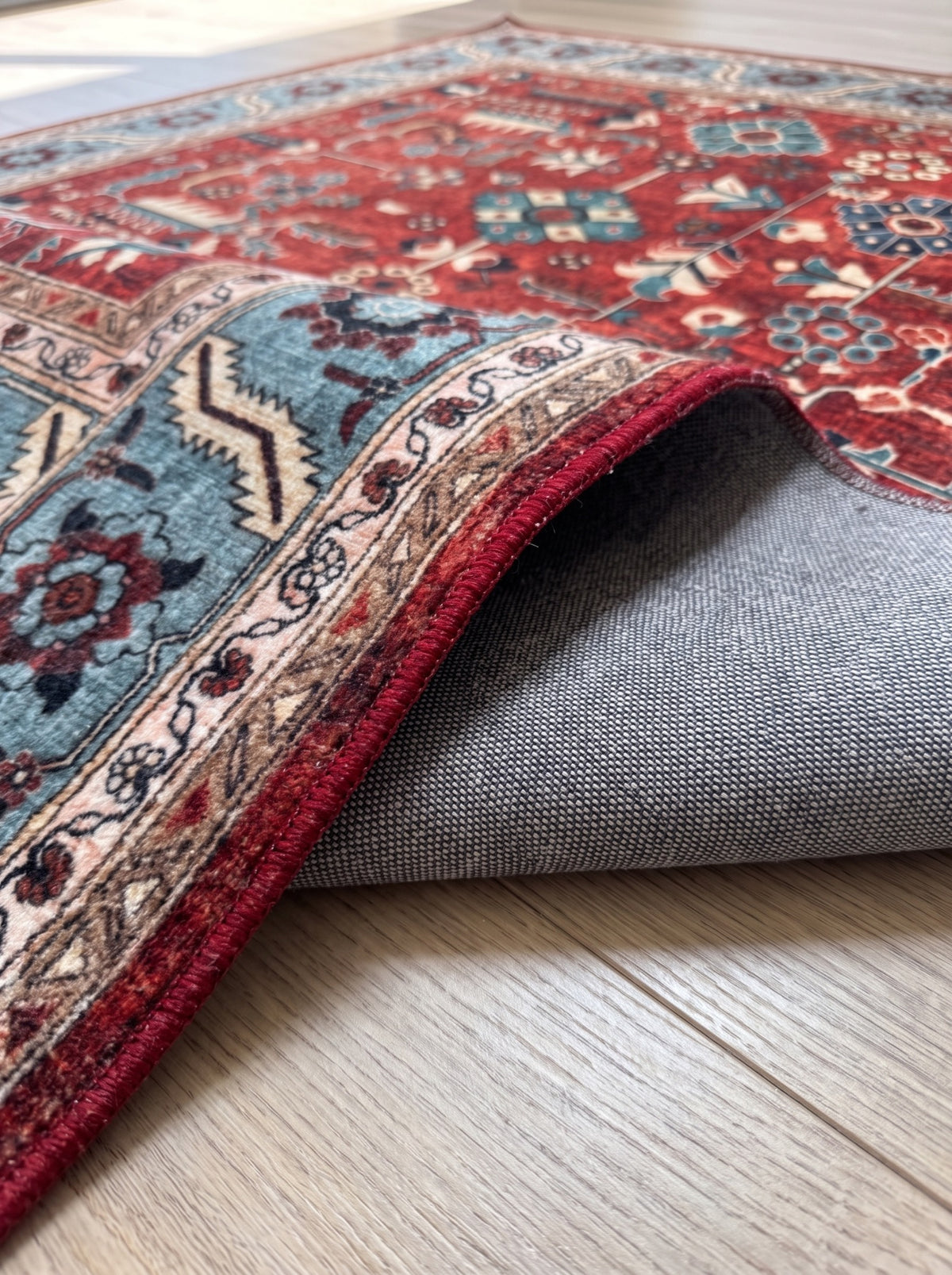 Folded corner of the Anatolian Heritage Turkish rug showing its grey woven backing and red bound edge