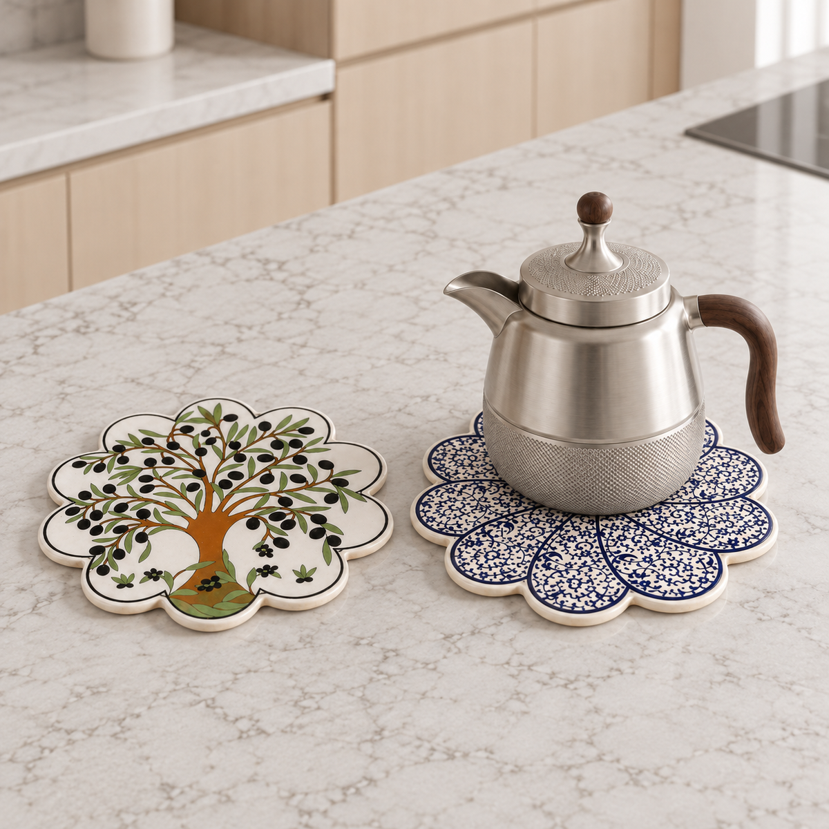 White-Blue ceramic trivet beneath a stainless-steel jug beside an Olive Tree trivet; jug not included
