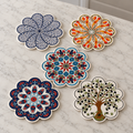 Five Turkish ceramic trivets, one each of White-Blue, Orange, Blue-White-Red, Navy and Olive Tree, arranged on pale marble