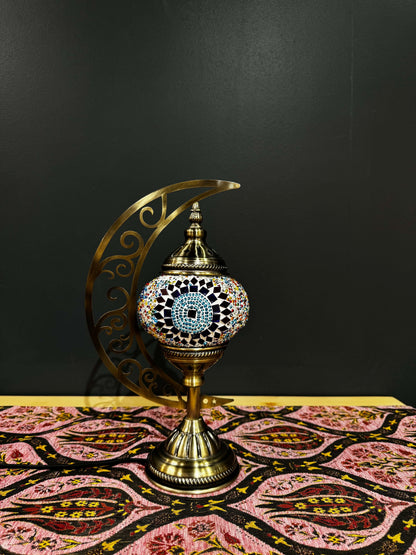 Sunburst Circle Turkish Mosaic Lamp with crescent moon stand, featuring vibrant mosaic design on a decorative table.