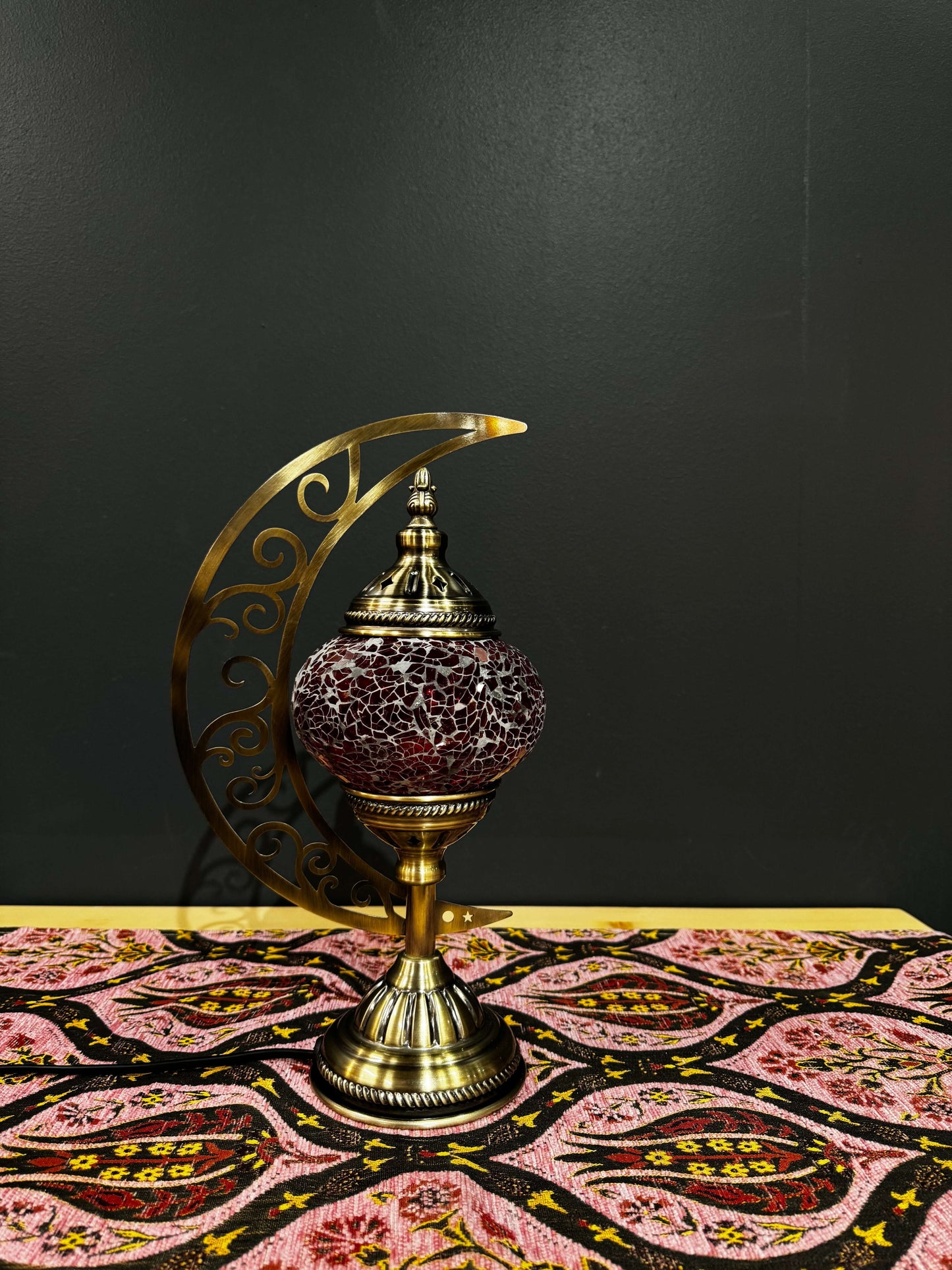 Crimson Glow Turkish Mosaic Table Lamp with crescent moon design and intricate scrollwork on a decorative tablecloth.