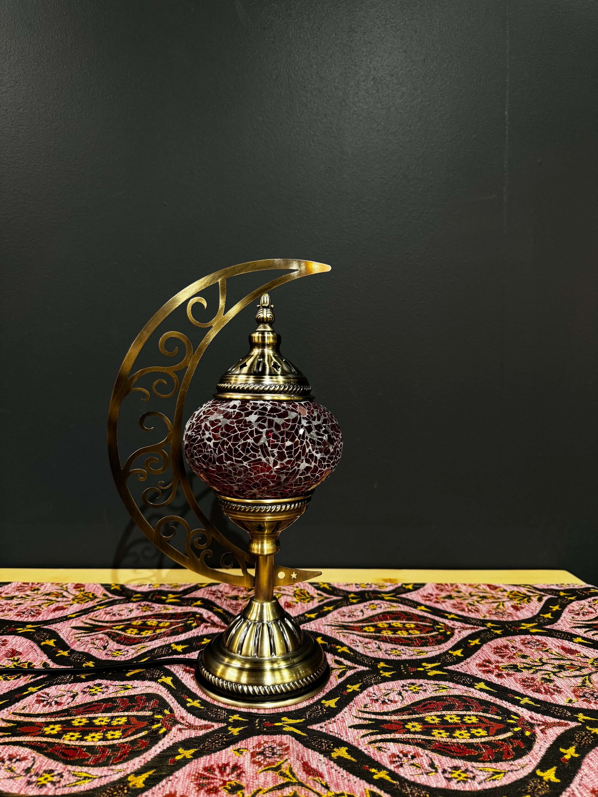 Crimson Glow Turkish Mosaic Table Lamp with crescent moon design and intricate scrollwork on a decorative tablecloth.