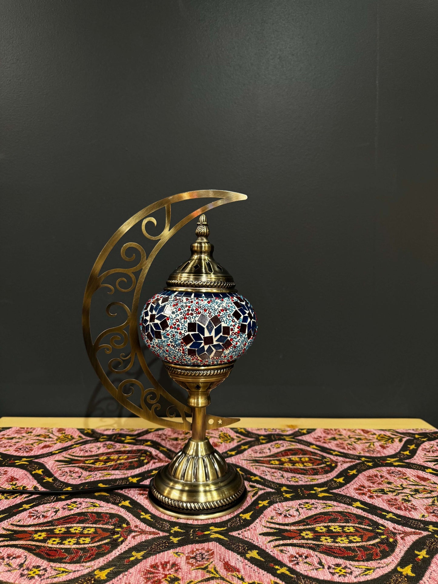 Ruby Blossom Mosaic Table Lamp with crescent moon stand, showcasing vibrant red, white, and blue glass design on a decorative table.