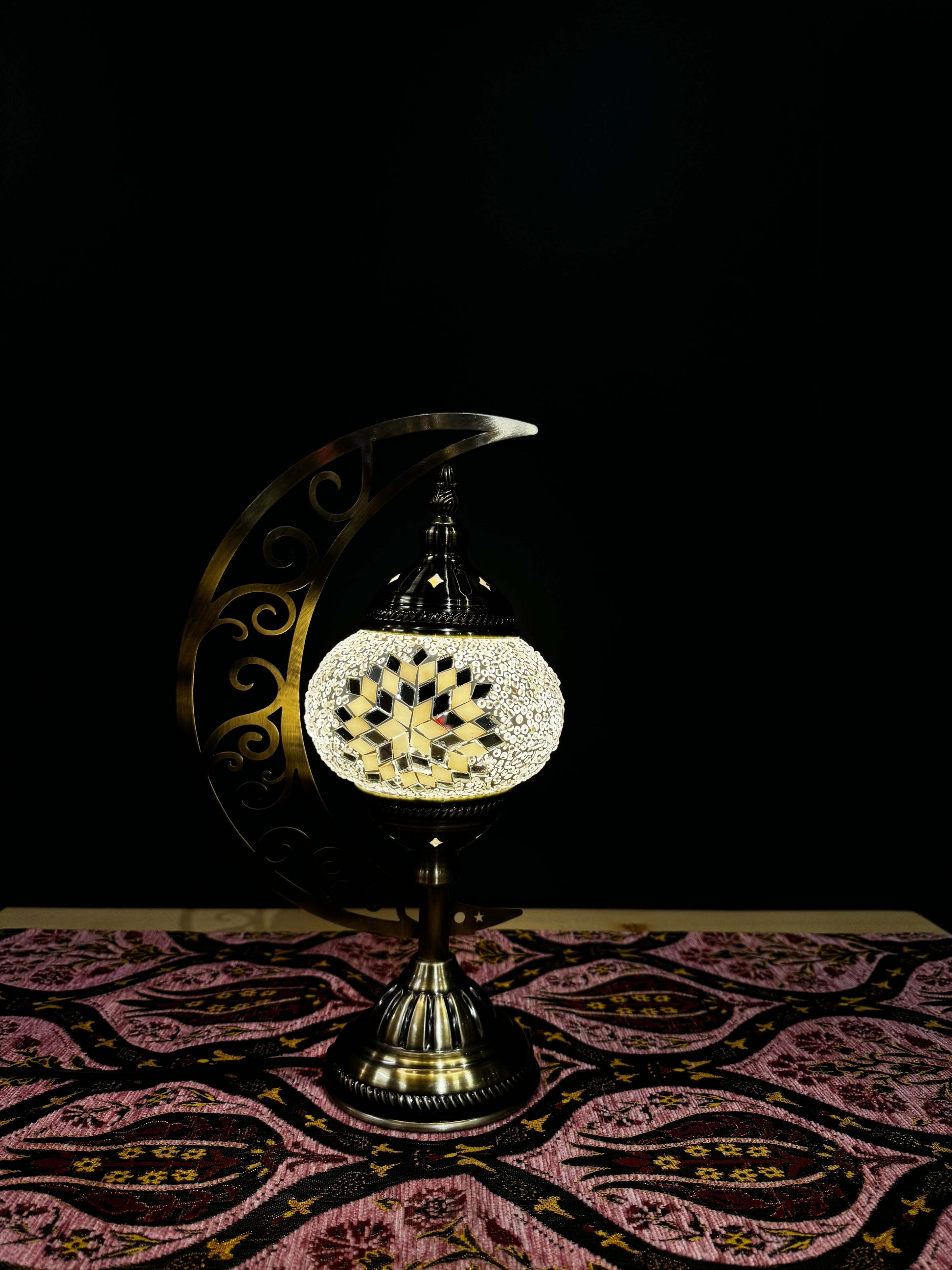 Midnight Glow Turkish mosaic table lamp on crescent moon stand, featuring a black and white design with red accents.