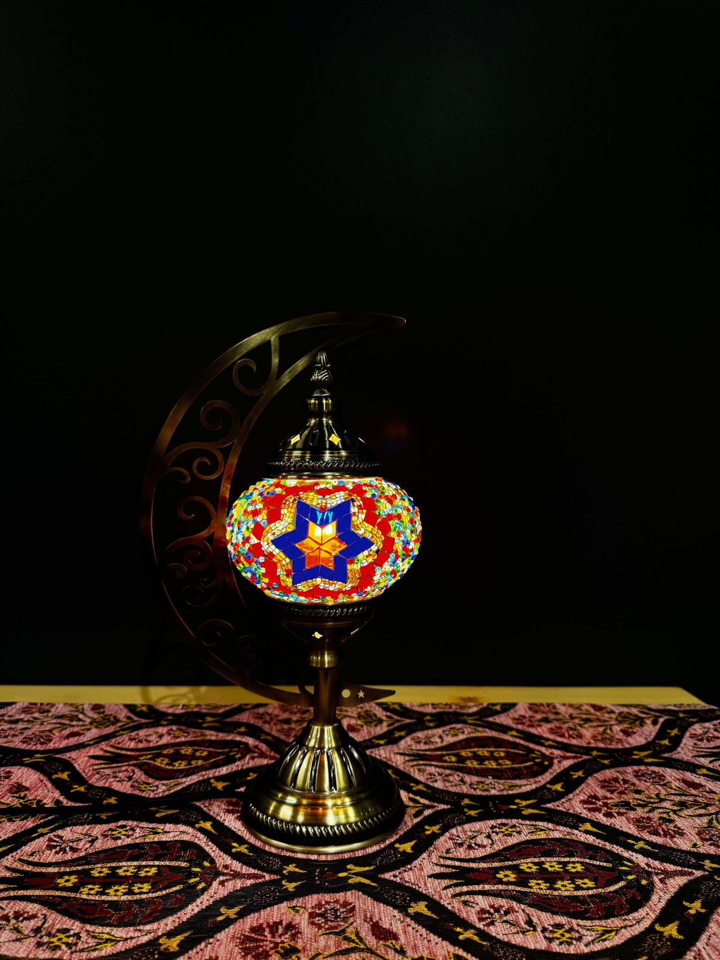 Radiant Starburst Turkish Mosaic Lamp with crescent moon stand on decorative tablecloth.