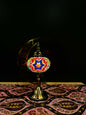 Radiant Starburst Turkish Mosaic Lamp with crescent moon stand on decorative tablecloth.