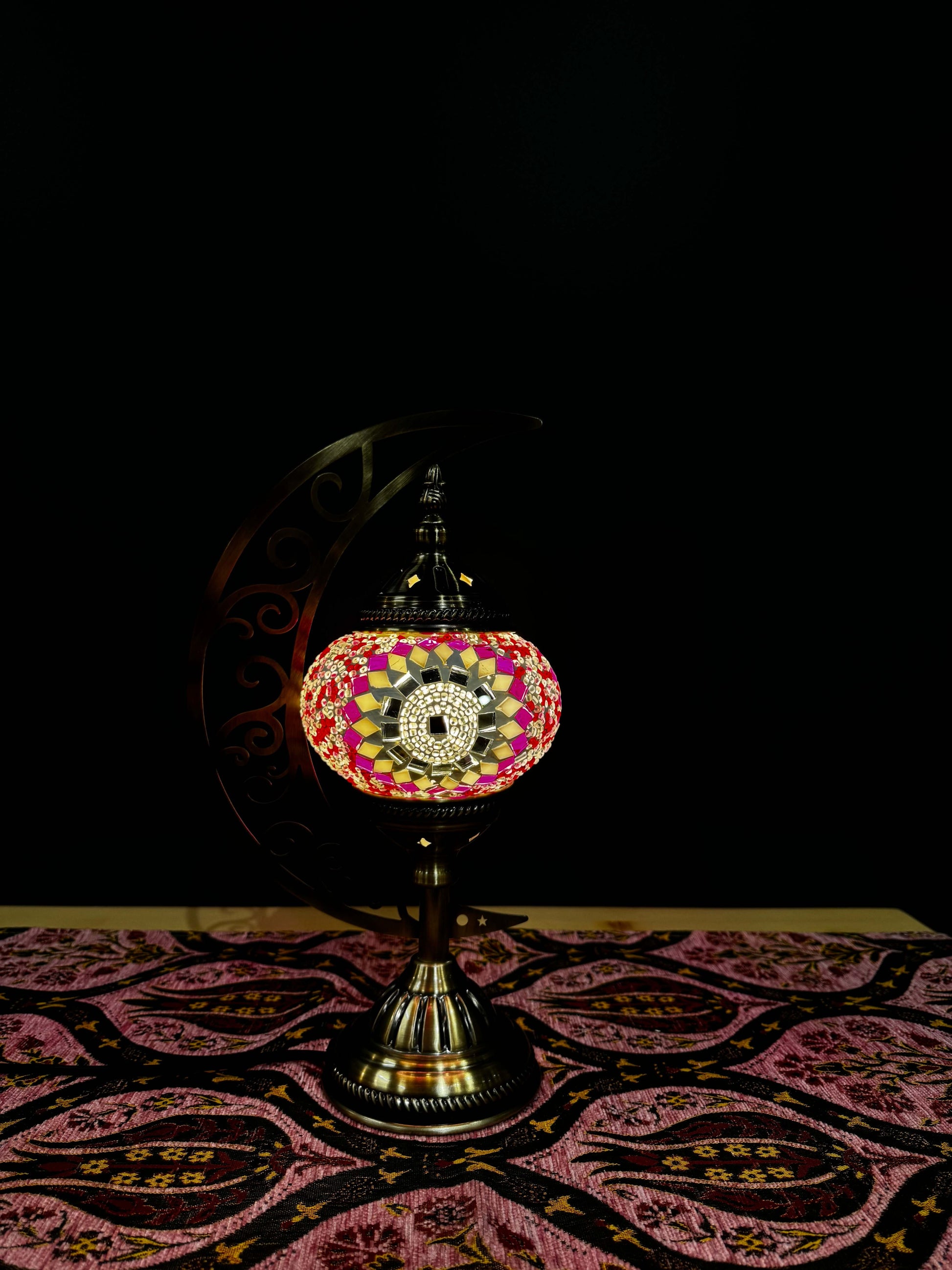 Blush Radiance Turkish Mosaic Lamp with crescent moon stand, featuring intricate pink and gold mosaic patterns on a table.