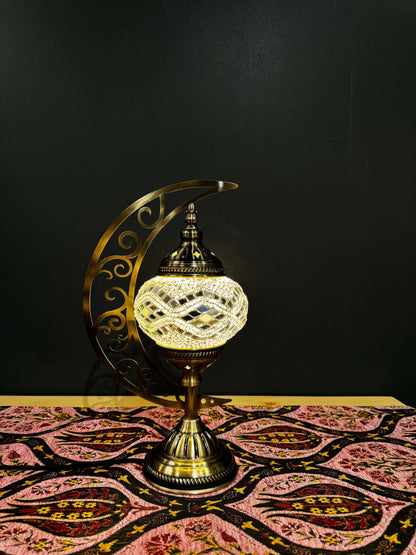 Ivory Wave Turkish Mosaic Lamp with crescent moon stand, showcasing intricate scrollwork and radiant glass design on a patterned table.