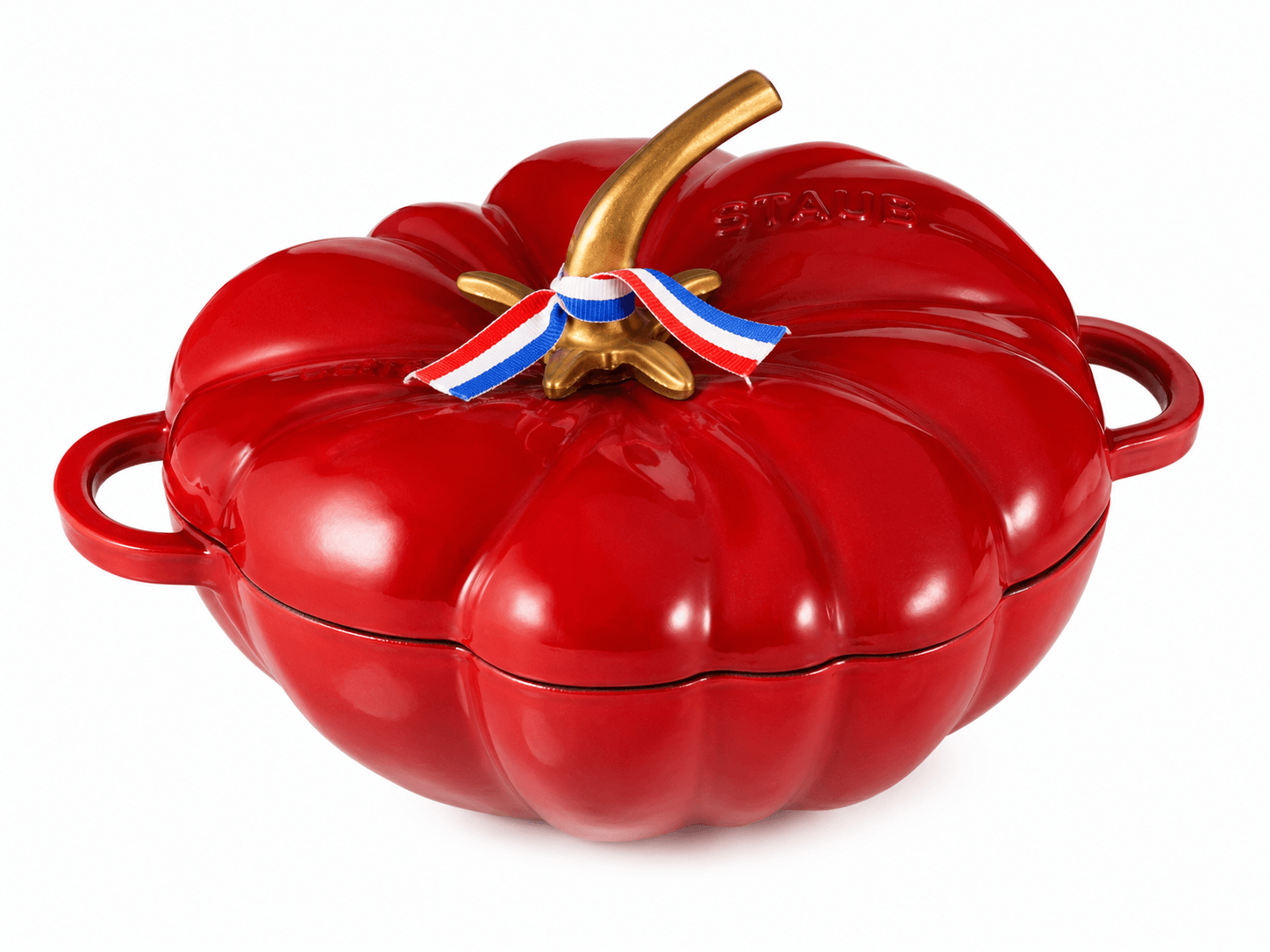 Staub pumpkin cocotte casserole pot in red cast iron with gold handle and tricolor ribbon decoration.