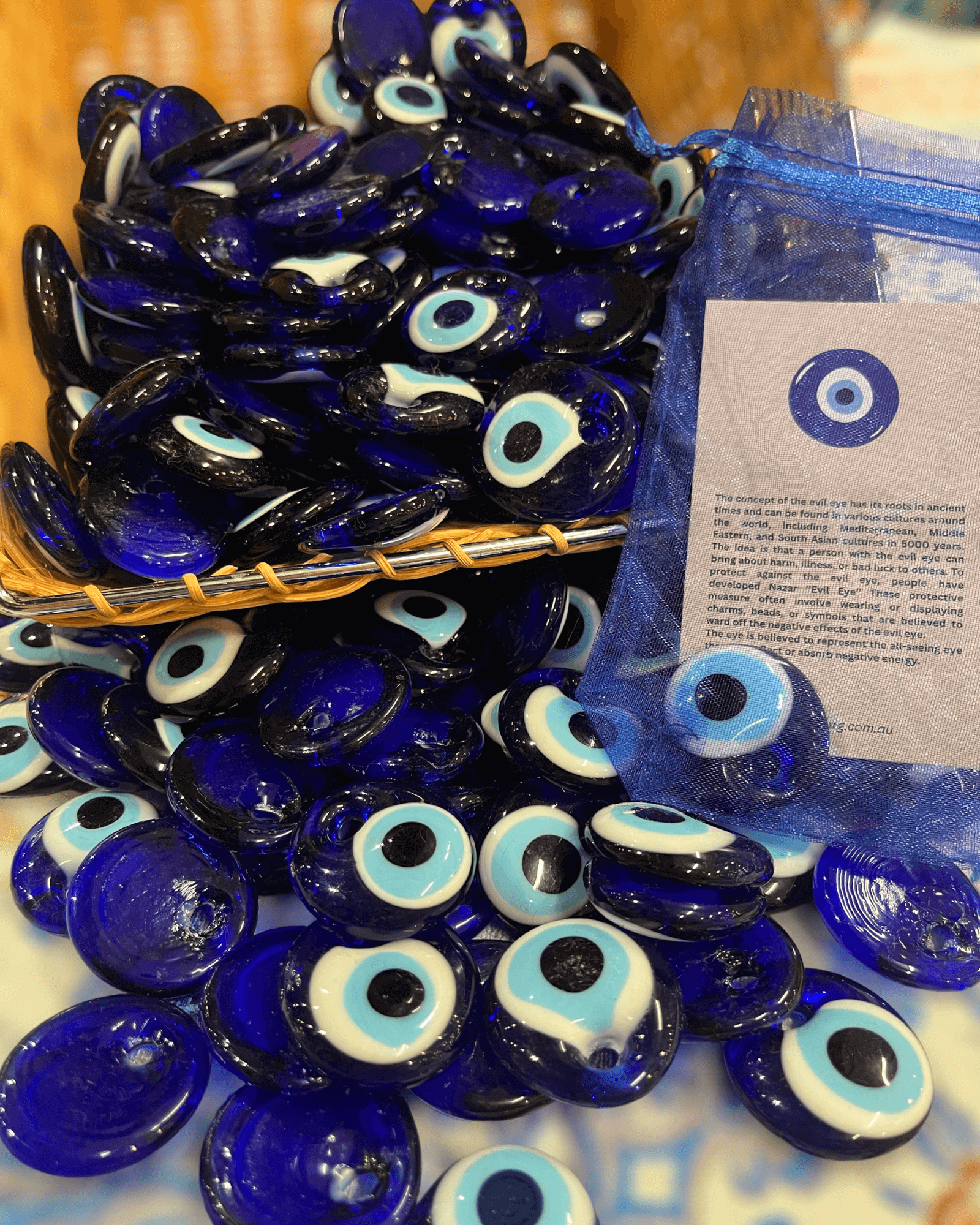A collection of evil eye beads (Nazar) in a basket, showcasing their beautiful blue and white glass design.