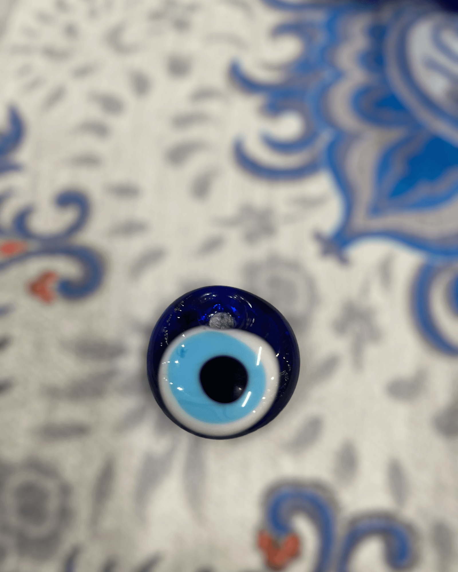 Evil eye bead (Nazar) on decorative surface, symbol of protection against negative energy.